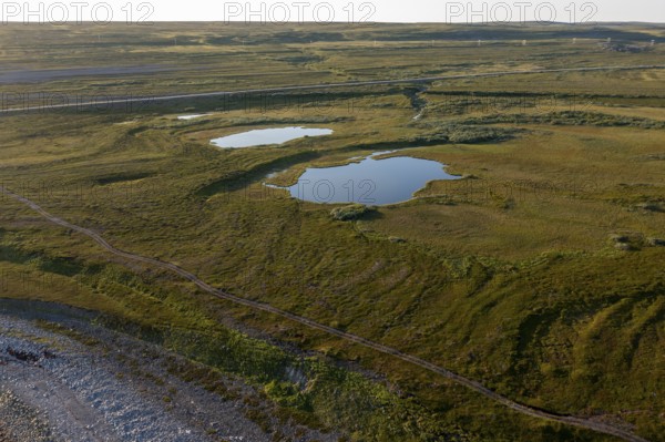 Coastal landscape on Varanger Fjord with blue sky, still sea, moors and pebble beach, Barents Sea, Finnmark, Norway