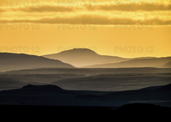 Silhouettes of mountains at sunset with yellow sky, near Vadsö, Finnmark, Norway
