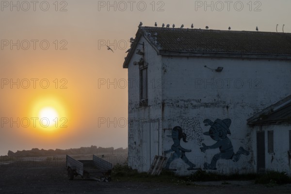 Abandoned building at sunset with graffiti and birds on the roof, Vardø, Finnmark, Norway