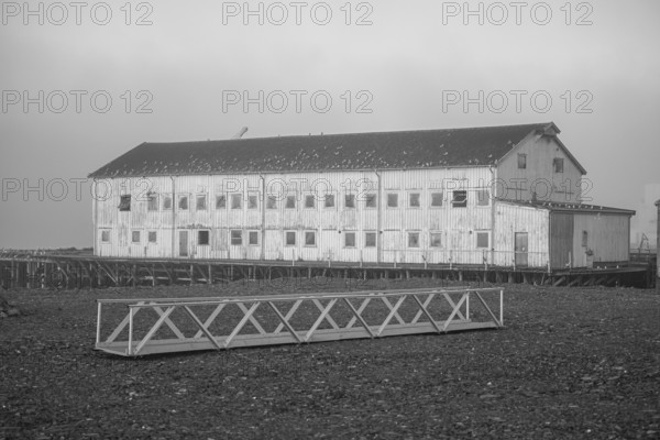 Elongated façade of an old port building in a foggy coastal atmosphere, Vardø, Finnmark, Norway