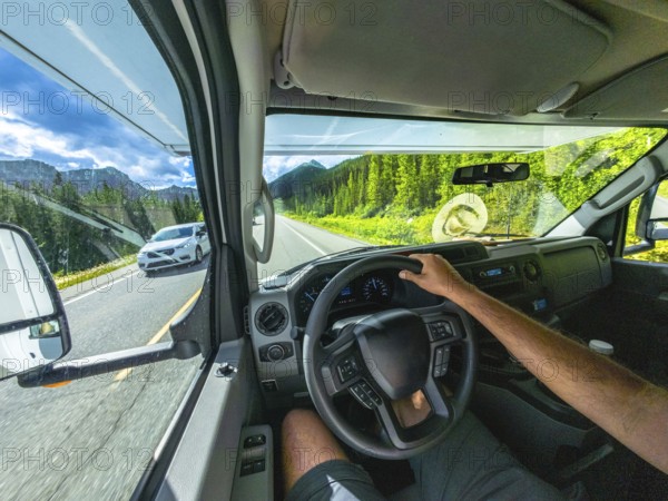 Pov driving a vehicle on the scenic icefields parkway in the canadian rockies with mountains and lush forests visible through the windshield on a sunny day