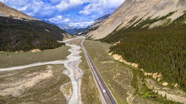 Sunti creek is flowing along the icefields parkway in the canadian rockies of jasper national park with sparse vegetation and coniferous forest growing on the slopes of the mountains