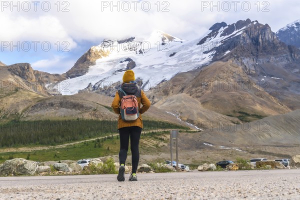 Female tourist walking towards athabasca glacier in jasper national park, alberta, canada, admiring the immensity of the glacier and surrounding mountains