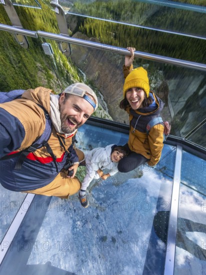 Happy family taking a selfie while standing on the glass floor of the glacier skywalk, enjoying the stunning view of the athabasca glacier and sunwapta valley in the canadian rockies