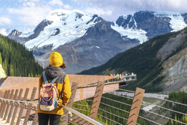 Tourist admiring breathtaking views of the canadian rockies from the glacier skywalk, a glass floored platform overlooking the athabasca glacier in jasper national park, alberta