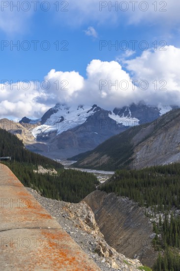 Breathtaking panorama from the skywalk reveals the majestic athabasca glacier surrounded by rugged peaks and lush pine forests in jasper national park under a vibrant blue sky