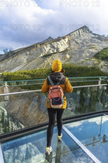 Hiker enjoying breathtaking view of sunwapta valley from glass floor on glacier skywalk at columbia icefield in jasper national park, alberta, canada