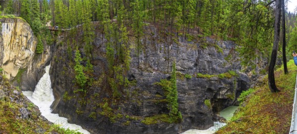 Panoramic view of sunwapta falls cascading through a narrow canyon surrounded by lush green forest in jasper national park, alberta, canada, creating a breathtaking natural wonder
