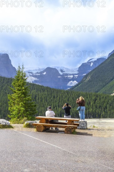 Tourists capturing breathtaking glacier views from a roadside stop along the scenic icefields parkway in the canadian rockies, appreciating the natural beauty