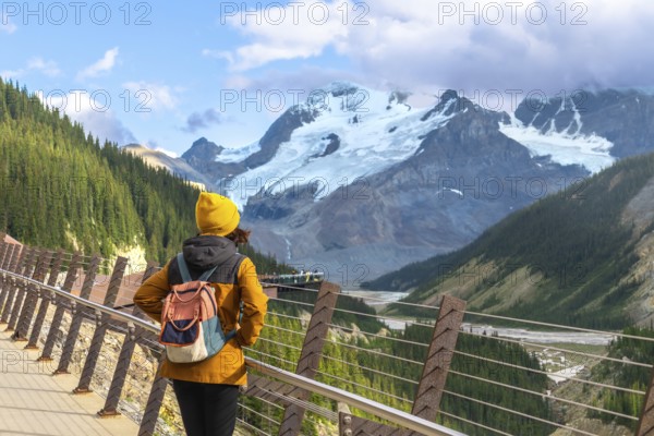 Tourist admiring athabasca glacier from the skywalk in jasper national park, experiencing the stunning beauty of the canadian rockies with breathtaking views of glaciers and mountains