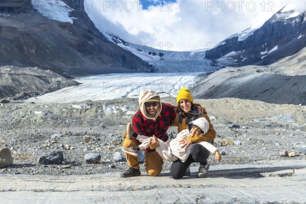 Happy family is having fun while visiting the athabasca glacier in the canadian rockies, jasper national park, alberta, canada, during a sunny day