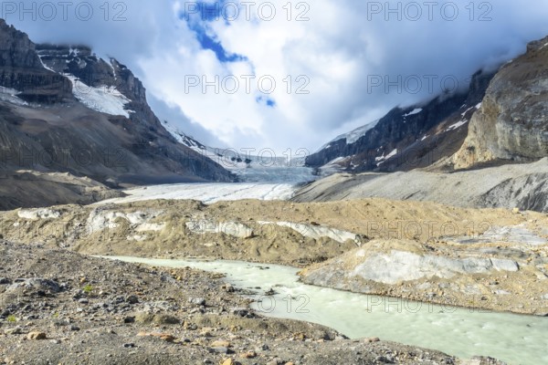 Turquoise meltwater flows from athabasca glacier in jasper national park, showcasing the effects of climate change on the canadian rockies landscape