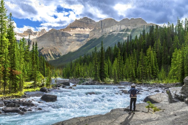 Hiker enjoying breathtaking views of turquoise waters flowing through mistaya canyon in banff national park, with the canadian rockies rising in the background