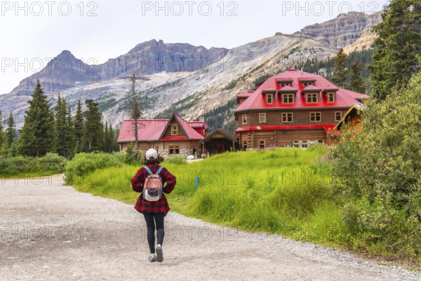 Female tourist walking on a gravel path towards the historic num ti jah lodge at bow lake in the canadian rockies of banff national park, alberta, with stunning mountain scenery in the background