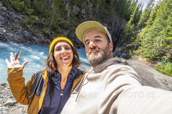 Happy couple of hikers taking a selfie at the turquoise river along the ci fuentes path waterfall trail on the icefields parkway in the canadian rockies, alberta, canada