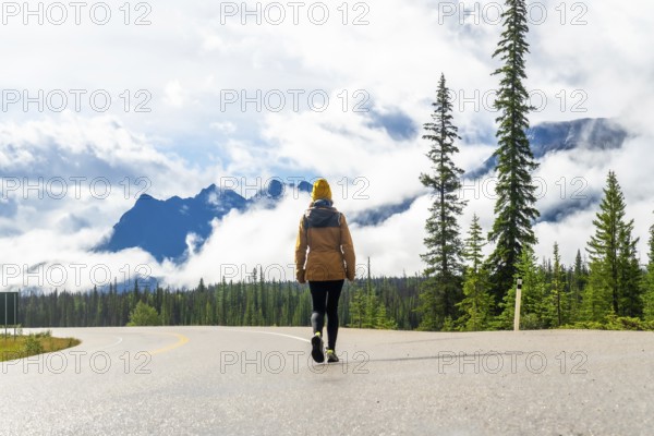 Tourist walking along the scenic icefields parkway, surrounded by majestic mountains and lush forests in the canadian rockies, embracing adventure and freedom