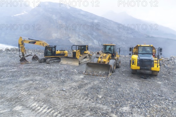 Excavator, bulldozer, and dump truck parked on gravel near athabasca glacier, highlighting industrial operations within the stunning landscape of jasper national park