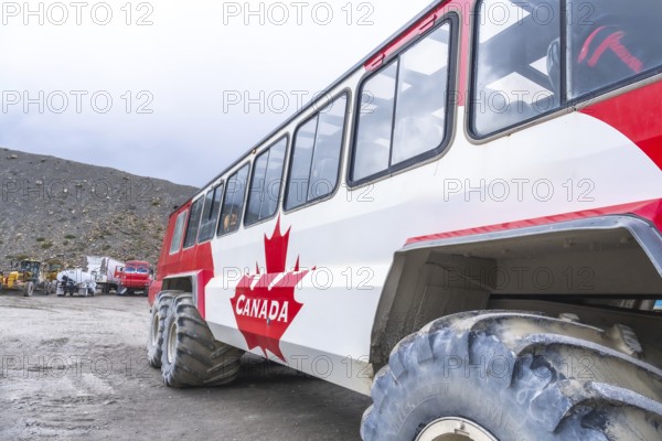 Red and white large tourist bus parked on the athabasca glacier in jasper national park, alberta, showcasing off road capabilities for glacier exploration