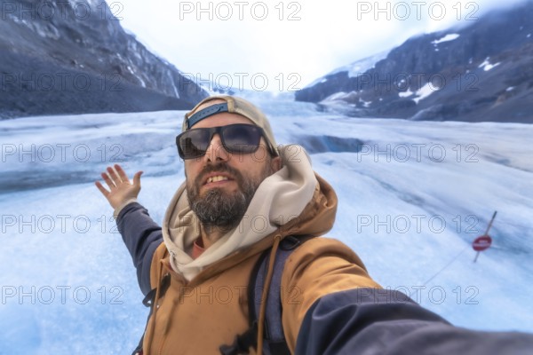 Hiker capturing a selfie with the stunning athabasca glacier in jasper national park, highlighting the majestic columbia icefield on a sunny summer day