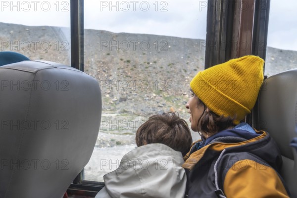 Mother and son are enjoying the view of athabasca glacier from a bus window during a sightseeing tour in jasper national park, showcasing the impact of climate change on glacial landscapes