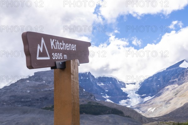 Brown wooden kitchener sign marking an altitude of 3505 meters, with the athabasca glacier and columbia icefield under a cloudy blue sky in jasper national park, alberta