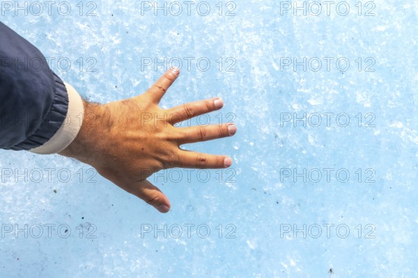 Hand of a tourist touching the millennial ice of athabasca glacier in the columbia icefield, inside jasper national park, a famous travel destination in the canadian rockies