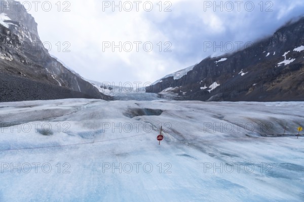 Scenic view of the receding athabasca glacier in jasper national park, illustrating climate change's impact on the canadian rockies with warning signs marking hazards