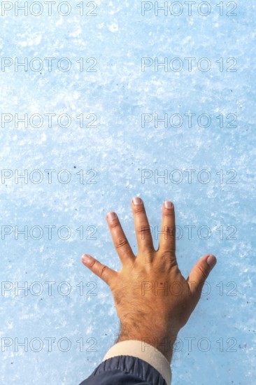 Tourist in a jacket touching the ancient ice of athabasca glacier in jasper national park, emphasizing the effects of climate change and glacial retreat