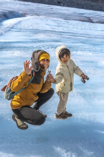 Mother and her son are enjoying their time on the athabasca glacier, waving happily amidst the stunning icy landscape of jasper national park in the canadian rockies