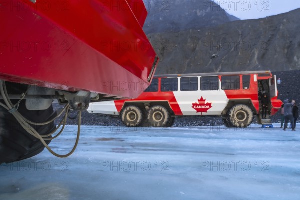 Red ice explorer buses standing on the athabasca glacier in the columbia icefield area of jasper national park in the canadian rockies of alberta, canada, offer tourists a unique experience