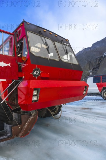 Red ice explorer bus parked on the athabasca glacier, offering breathtaking views of the canadian rockies in jasper national park, a popular tourist destination for exploring glaciers