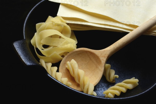 Lasagna leaves, fettuccine and fusilli in pot with cooking spoon
