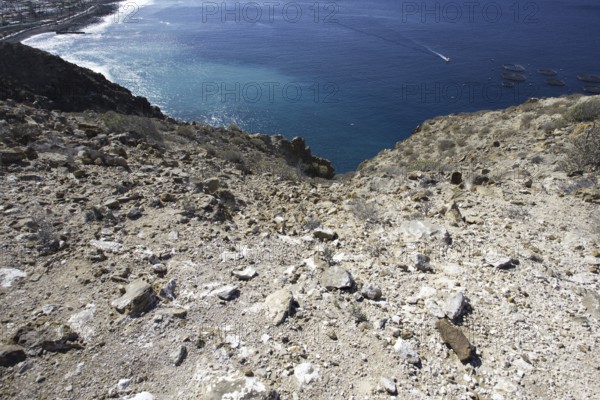 View of the deep blue sea from a rocky slope, with the coast running in the background, Los Cristianos Tenerife
