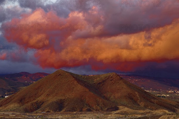 Dramatic cloud formations in shades of red over a mountainous landscape at sunset, Los Cristianos Tenerife