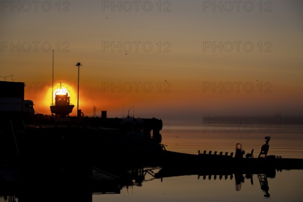A quiet evening mood in the harbor with a boat in the foreground and a sunset in the background, Vardø, Finnmark, Norway