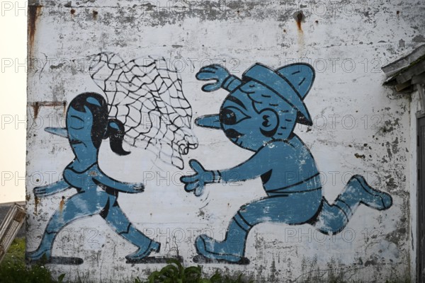 Mural in which a fisherman catches a woman with a net. By Husk Mit Navn. Vardö street art phenomenon created by the festival Komafest, curated by artist Pøbel in 2012, Vardø, Finnmark, Norway