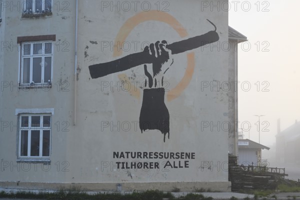 Wall painting with stretched arm and gaff. The inscription says Natural resources belong to everyone. Fishing protet on the Barents Sea against fishing quotas, Vardø, Finnmark, Norway