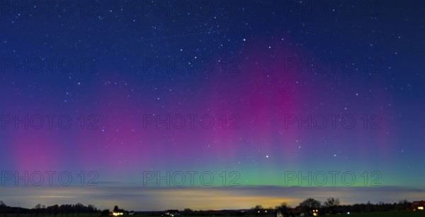 Glowing polar lights in shades of purple and green under a clear starry sky, EXPO Observatory Melle, Lower Saxony, Germany