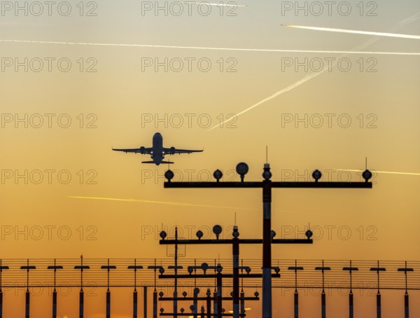 Runway lighting, approach aids, at Düsseldorf International Airport, sunset, aircraft taking off, Hauptbahn Süd, 05R/23L, contrails from aircraft at higher altitudes, North Rhine-Westphalia, Germany