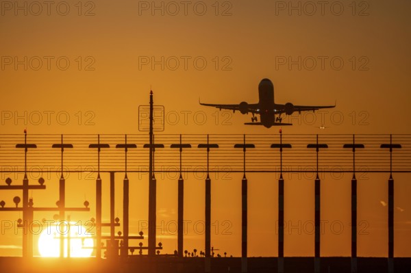 Runway lighting, approach aids, at Düsseldorf International airport, sunset, aviator taking off, in the background aircraft landing on the main runway south, 05R/23L, North Rhine-Westphalia, Germany