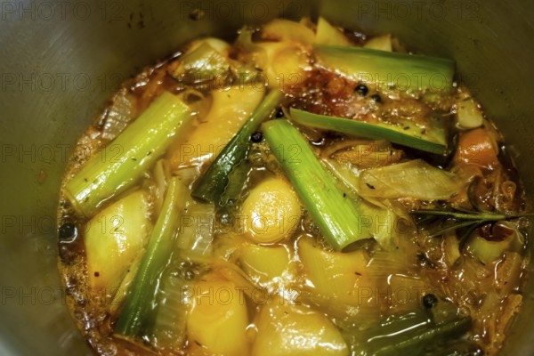 A vegetable stock is cooked, various vegetables are boiled with spices and herbs in water for a long time to make a stock that can be used as vegetable soup or as a base for sauces or other dishes