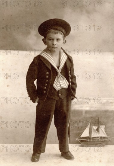 Historical cabinet card, boy in sailor suit against maritime studio backdrop with sailing ship, around 1900, Germany