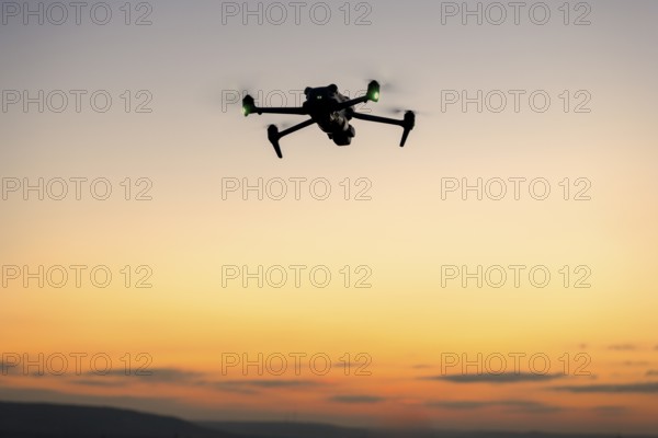 Drone in silhouette flying in front of a colorful sunset