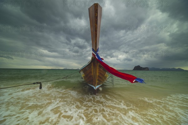 Longtail boat on the beach with dark rain clouds behind it, Koh Ngai island, Andaman Sea, Satun province, southern Thailand, Thailand