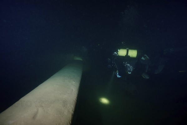 Diver examines a lediwreck, wreck of a lediship, ledi ship, cargo ship for mass freight, bulk cargo, at night in Lake Walen. Tauchplatz Känzeli, Mols, Canton of St. Gallen, Switzerland
