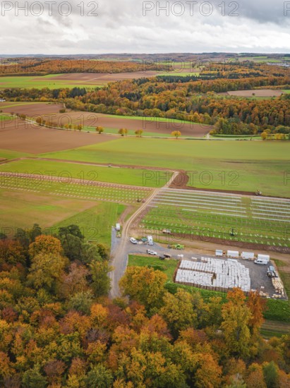 Aerial view of an autumn landscape with colorful trees and fields under cloudy sky, Energiewende, construction of PV open space, Baden-Württemberg, Germany