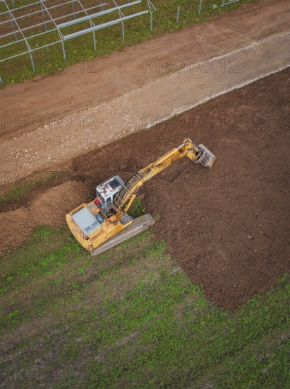 Excavator shapes the earth on a large field viewed from above, Energiewende, construction of PV open space, Baden-Württemberg, Germany