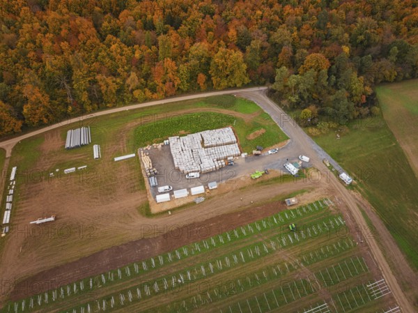 Large-scale warehouse with building materials and vehicles, surrounded by autumn landscape and fields, energy transition, construction of PV open space, Baden-Württemberg, Germany
