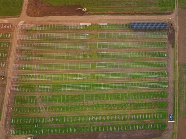 Large-scale solar frame construction on a field, surrounded by farmland seen from the air, energy revolution, construction of PV open space, Baden-Württemberg, Germany