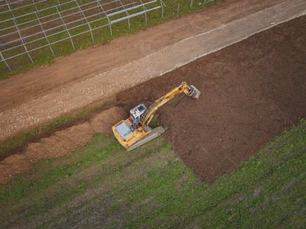 Aerial view of an excavator working a field and moving soil, Energiewende, construction of PV open space, Baden-Württemberg, Germany